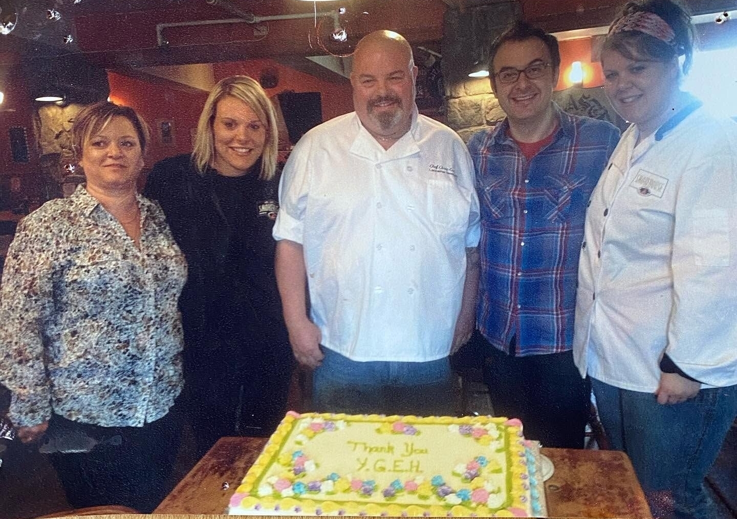 Chris and Cathy Corrigan stand with their family and host John Catucci at The Lancaster Smokehouse after filming their “You Gotta Eat Here!” episode, posing behind a decorated cake that reads “Thank You Y.G.E.H.”
